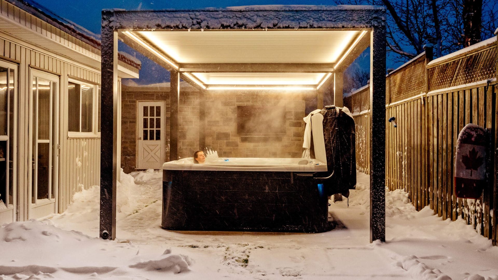 Outdoor hot tub with covered seating area in a snowy backyard with spa cover folded